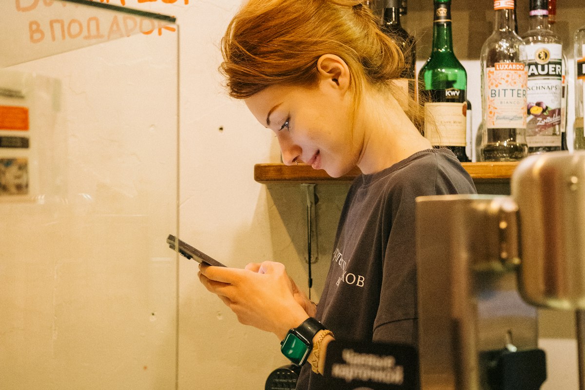 Woman using a phone behind a bar counter