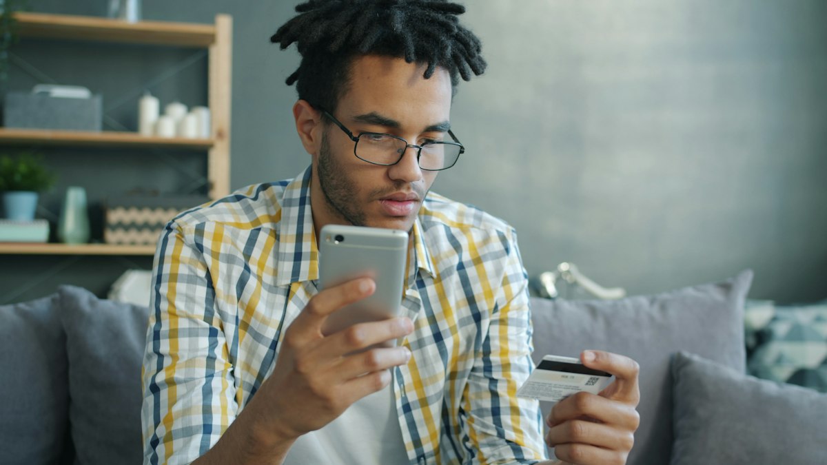 Shopper holding a credit card and smartphone while buying online